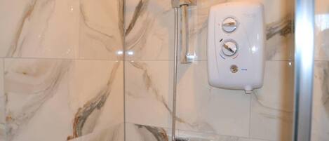 Ducha con cabezal de ducha de mano y panel de control en la pared.