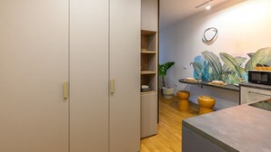 Et moderne køkken med indbygget ovn, mikroovn og et lille spiseområde med barstole.