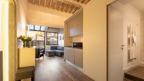A compact living space with a kitchenette, a sofa, a dining area, and a door leading to a bathroom. - San Lorenzo Terrace Apartment (Florence)