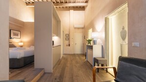 A hotel room with a bed, a sitting area with a chair, a small table, and a mirror. - San Lorenzo Terrace Apartment (Florence)