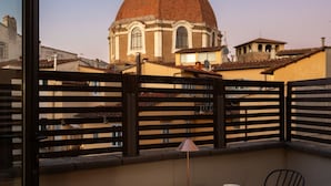 A balcony with a table set for two, a lamp, and a view of a historic building with a dome. - San Lorenzo Terrace Apartment (Florence)