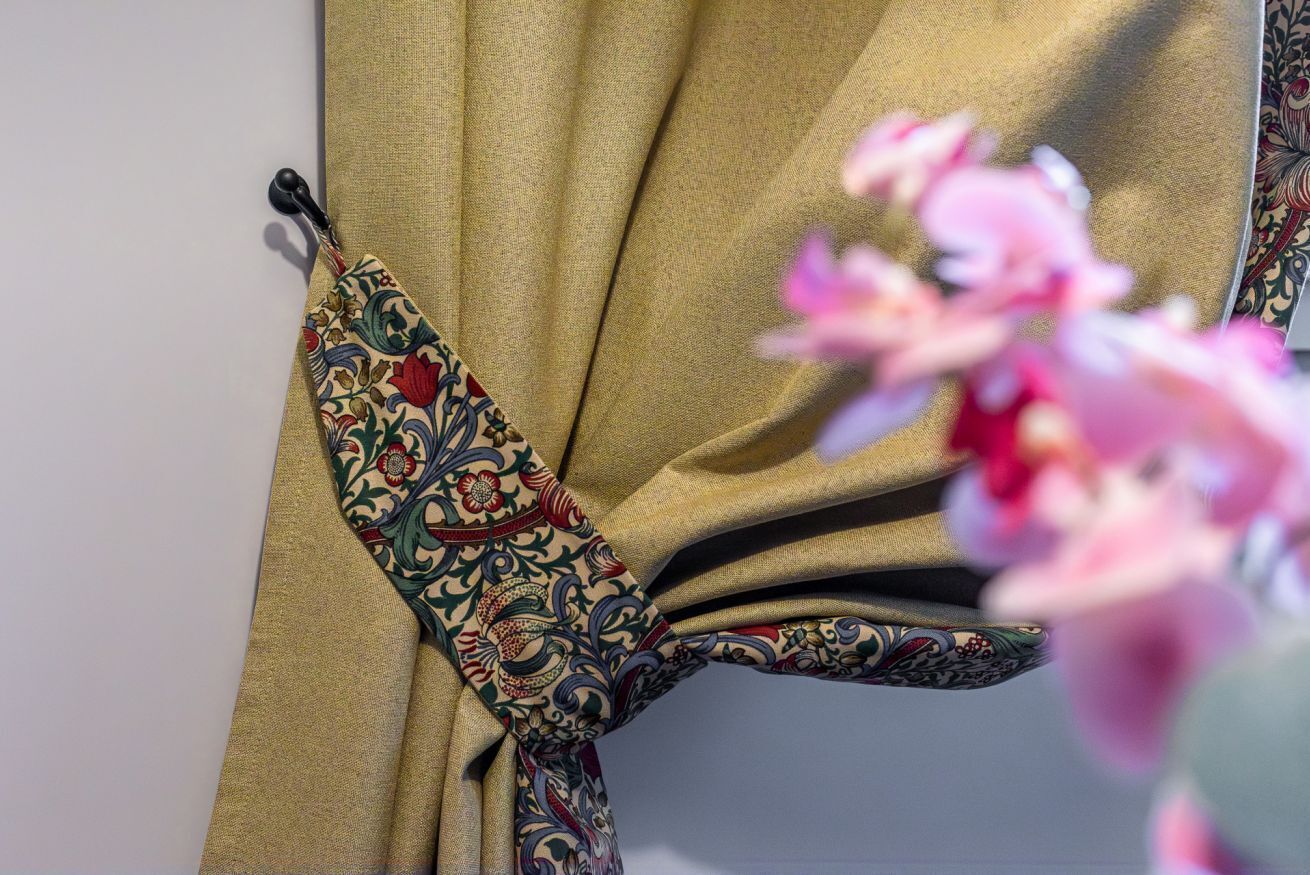 Un rideau orné d’un motif floral et agrémenté d’une frange.