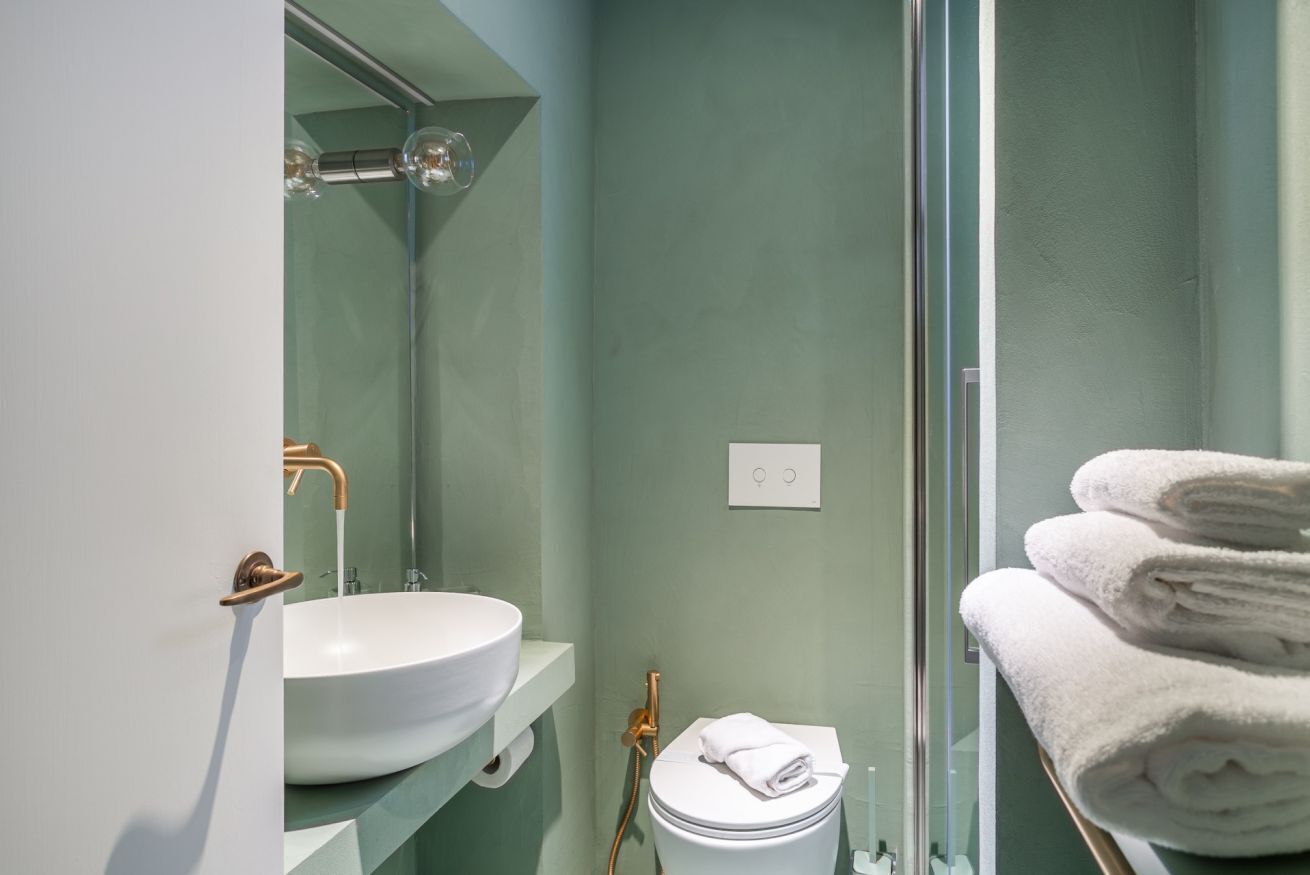 A bathroom with a white sink, a mirror, a toilet, and a glass shower enclosure.