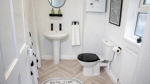 Un baño con lavamanos blanco, inodoro, espejo y radiador.