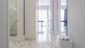 A hallway with a marble floor, a white door, and a bathroom with a sink and mirror. - Modern Catskills Mountain Retreat with Rooftop Hot Tub on 22 Private Acres (Denver)
