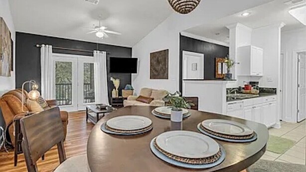 A modern dining area with a round table set for four, a sofa, and a kitchen in the background. - Park Avenue 813 - Heart of Foley (Foley)