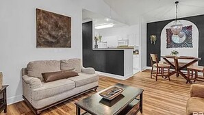A modern living room with a sofa, coffee table, and dining area with chairs and a table. - Park Avenue 813 - Heart of Foley (Foley)