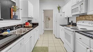 A modern kitchen with white cabinets, a black countertop, and a tiled floor. - Park Avenue 813 - Heart of Foley (Foley)