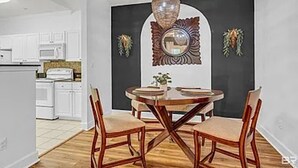 A dining area with a round table and chairs, a hanging light fixture, and a decorative mirror on the wall. - Park Avenue 813 - Heart of Foley (Foley)