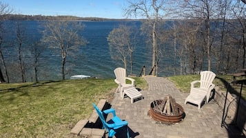 Un patio sul lago con poltrone Adirondack, un braciere e vista sul lago.