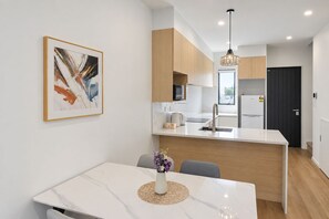 A modern kitchen with a central island, white cabinetry, and a pendant light.
