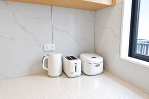 A kitchen with a marble backsplash, a kettle, a toaster, and a rice cooker on a countertop.