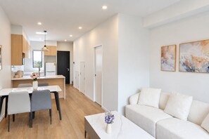 A modern apartment with a dining area, kitchen, and living room.