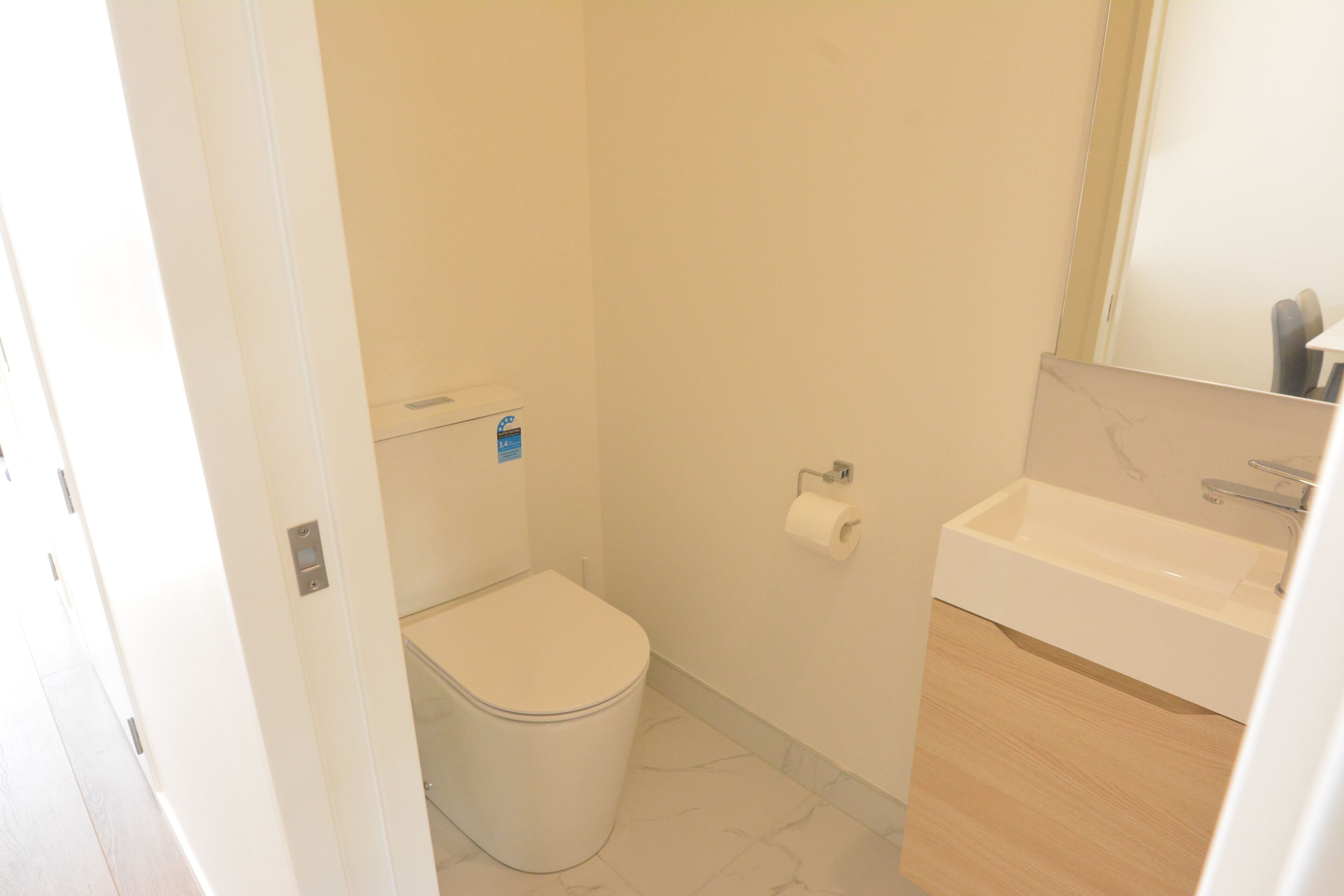A small, clean bathroom with a toilet, sink, and mirror.