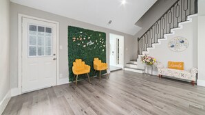 Ein modernes Interieur mit einer Treppe, einer grünen Wand mit floralen Dekorationen und einer Bank mit Kissen.