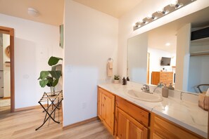 A modern bathroom with a large mirror, wooden cabinets, and a marble countertop.
