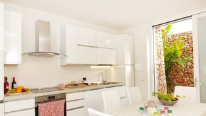 A modern kitchen with white cabinets, a built-in oven, and a dining area with a table set for four. - Modern 2-unit villa with heated pool and seaview (Leuca)