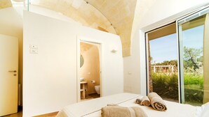 A hotel room with a bed, a bathroom, and a large window with a view of greenery. - Modern 2-unit villa with heated pool and seaview (Leuca)