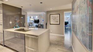 A modern kitchen with a central island, stainless steel appliances, and a dining area in the background. - LUXURY BEACH AVE 2 BED SUITE (Vancouver)