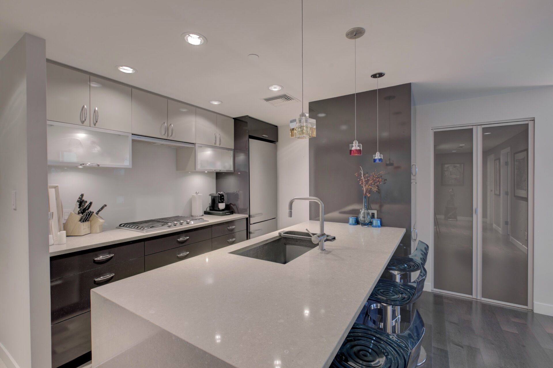 A modern kitchen with a large island, stainless steel appliances, and pendant lighting.