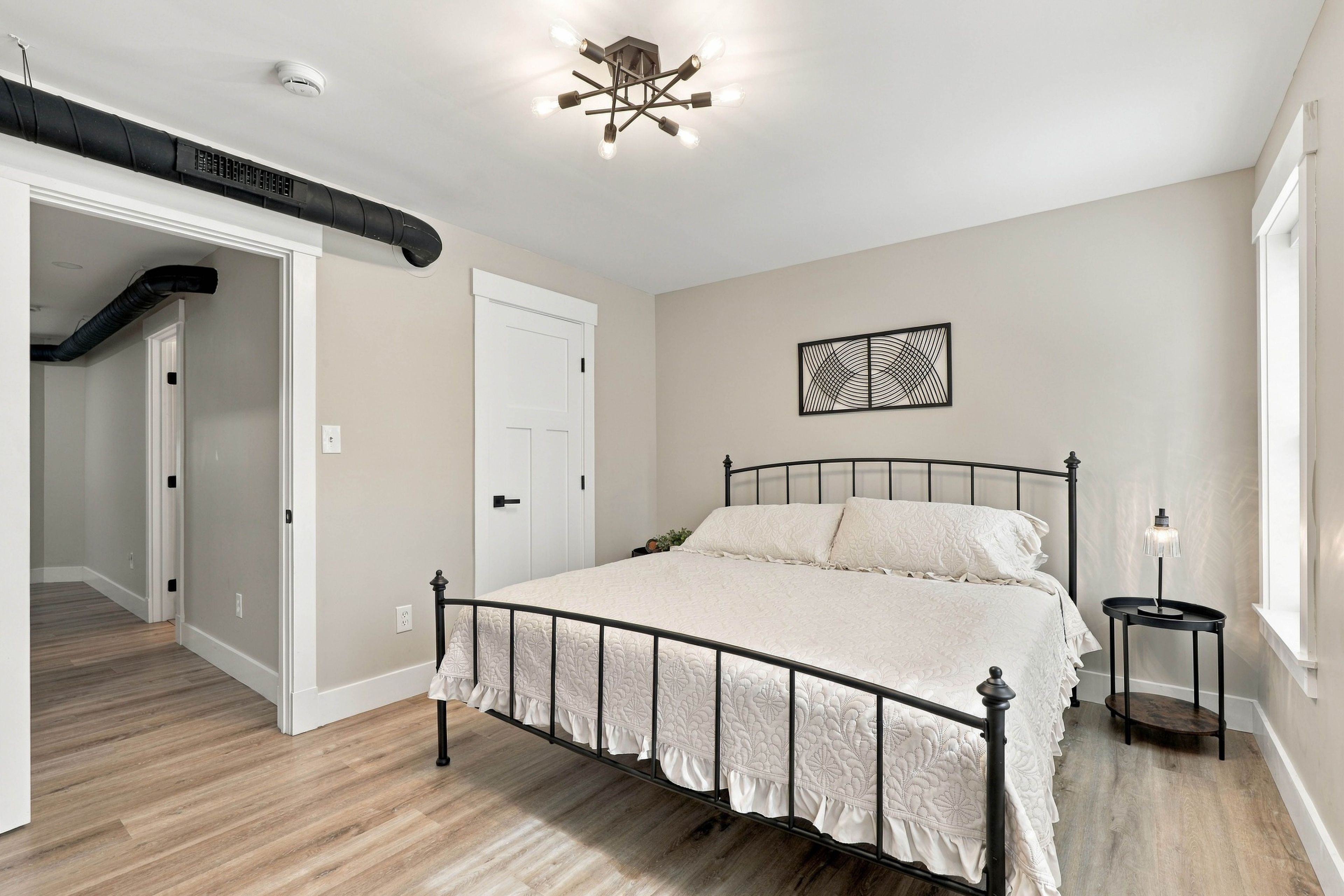 A bedroom with a bed, a bedside table, a wall art piece, and a ceiling light fixture.