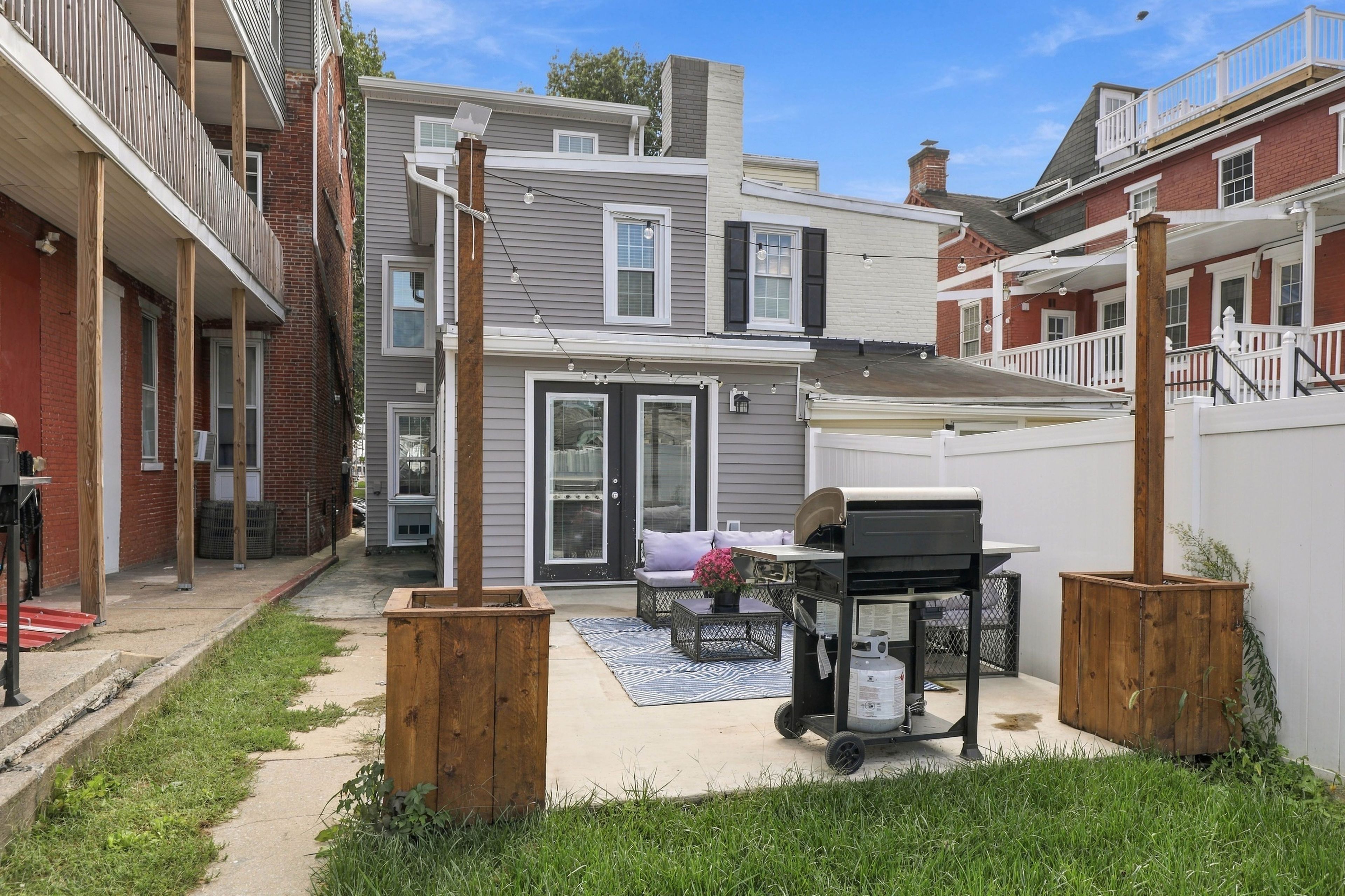 A residential backyard with a patio area, a grill, and a small seating arrangement.