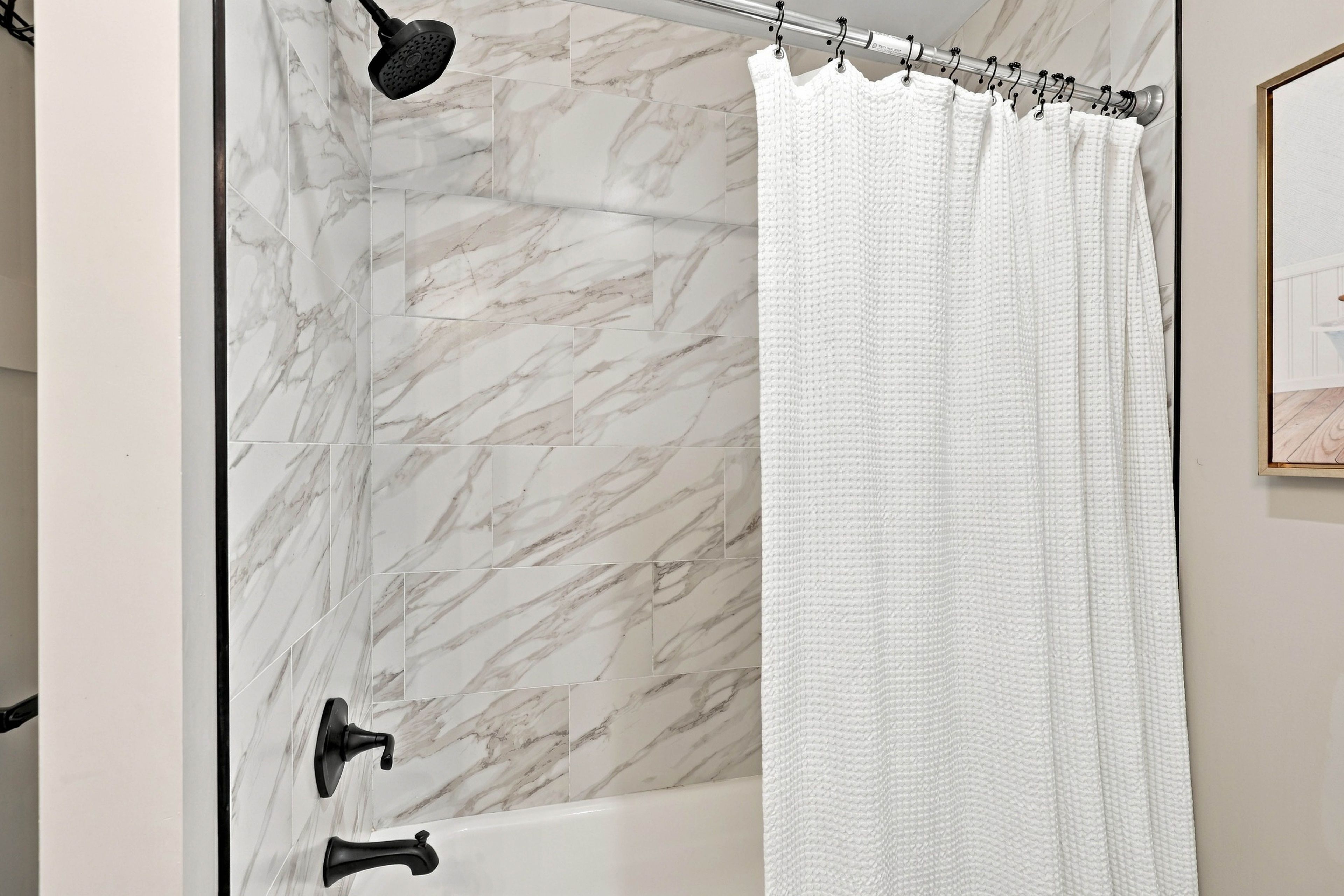 Un bagno con tenda da doccia, soffione a mano e rubinetto a muro.