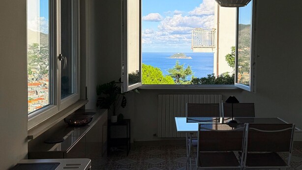 Eine kleine Küche mit Meerblick, ein Essbereich mit Tisch und Stühlen sowie eine Pendelleuchte.