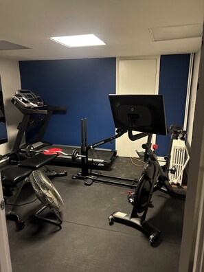 A gym with exercise equipment including a treadmill, stationary bike, and weight bench.
