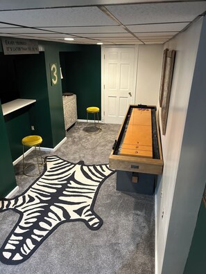 A pool table in a room with green walls, a zebra-patterned rug, and two yellow stools. - Spacious, Historic 6-bedroom Home next to Steelers/Pirates Stadiums (Pittsburgh)