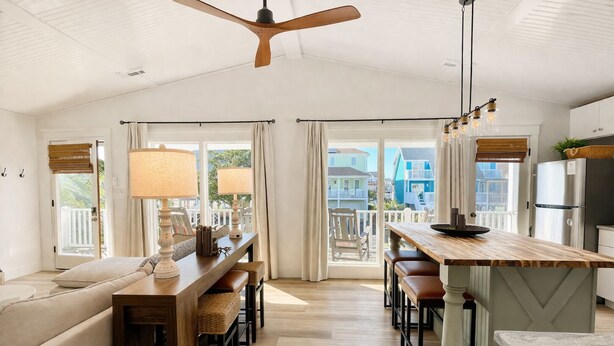 Un vaste espace de vie comprenant une table à manger en bois, un canapé et un ventilateur de plafond.