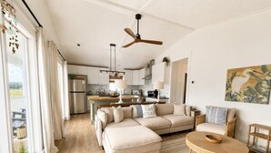 Un grand espace de vie comprenant un canapé, une table à manger et une cuisine à l’arrière-plan.
