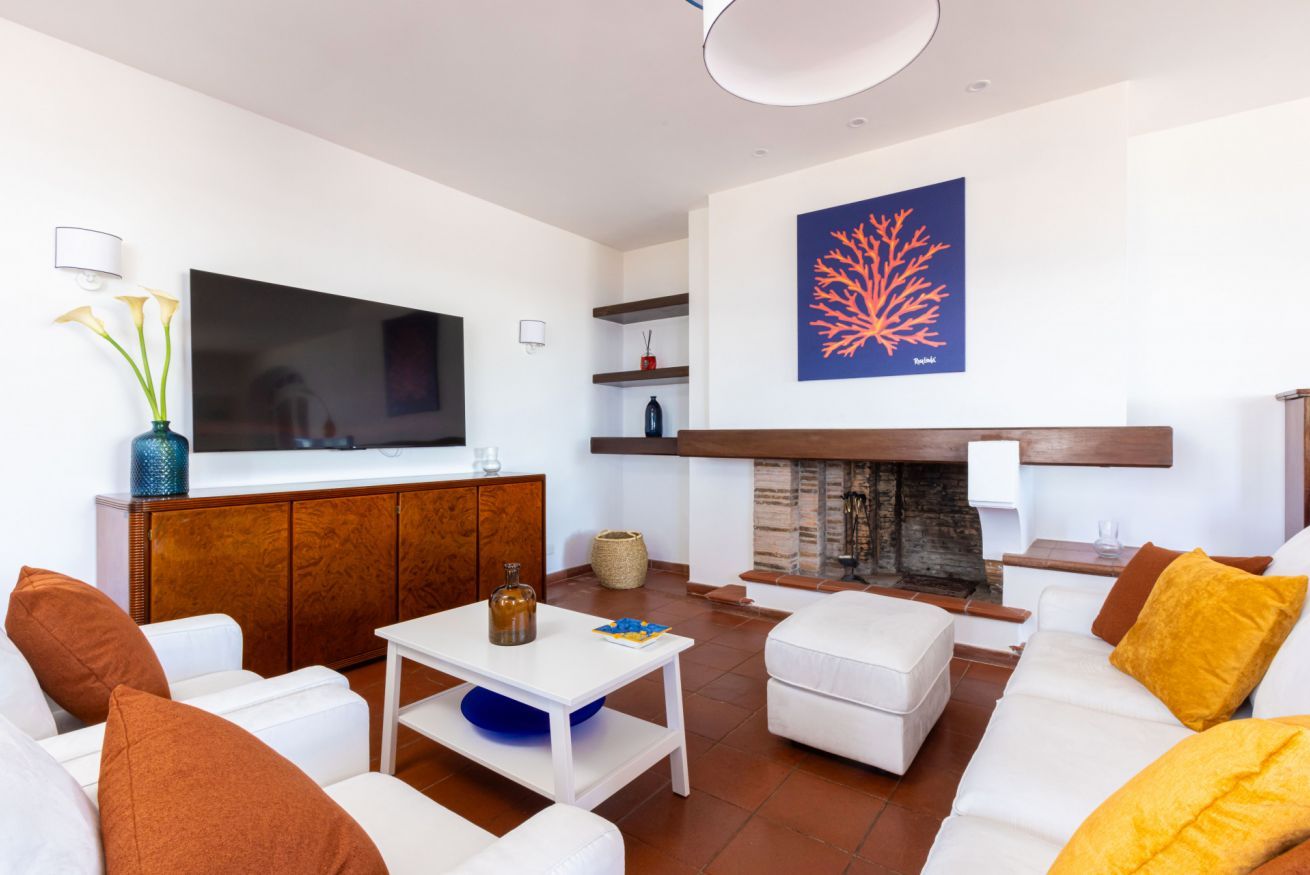 Ein modernes Wohnzimmer mit Flachbildfernseher, weißen Sofas, einem Couchtisch und einem Kamin.