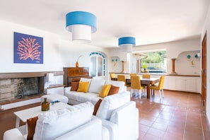 A spacious living area with a fireplace, white sofas, yellow chairs, and a dining table. - Seaview Luxury Villa with terrace, gym, jacuzzi, pool & bbq (Massa Lubrense)