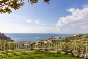 A coastal view with a clear sky, a fenced garden, and buildings in the distance. - Seaview Luxury Villa with terrace, gym, jacuzzi, pool & bbq (Massa Lubrense)