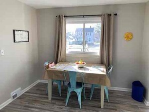 A dining area with a table, chairs, and a window with curtains. - Brick Ranch On A Quiet Street In Historic Bedford (Bedford)