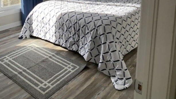 Un dormitorio con cama, una ventana con cortinas, un cuadro en la pared y una puerta.