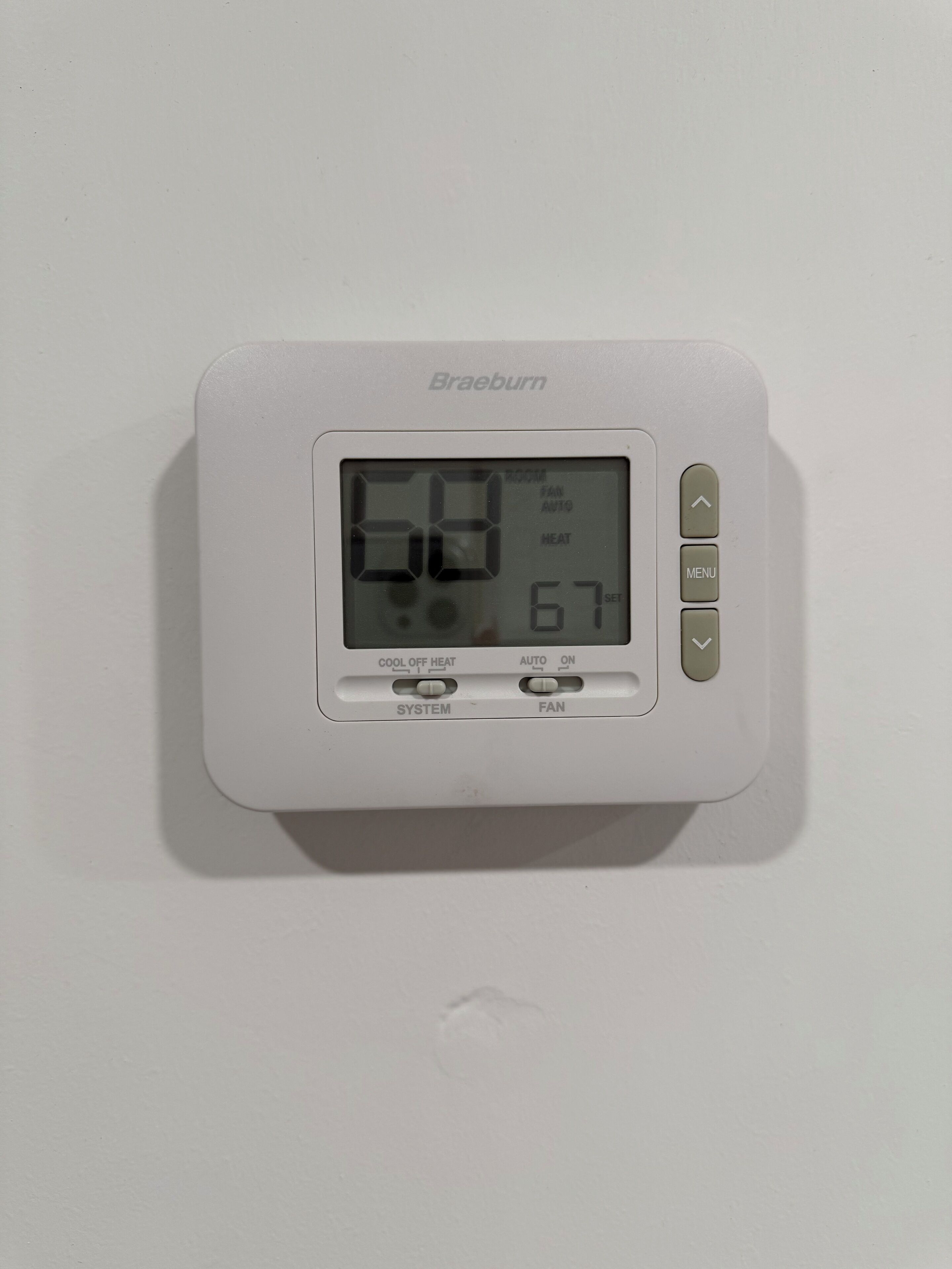 A Braeburn thermostat with a digital display, set to 68 degrees, and includes buttons for system, fan, and auto/manual settings.