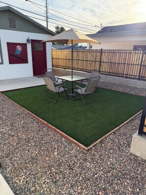 A patio area with a table and chairs, surrounded by artificial grass and a gravel border. - Perfect 1-bedroom bungalow with AC in beautiful Mesa 1 mile from Cubs Stadium (Mesa)