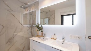 A bathroom with a marble shower, a white sink with two faucets, and a large mirror. - Los Cidrones Ubrique by Ruralidays (Cádiz)