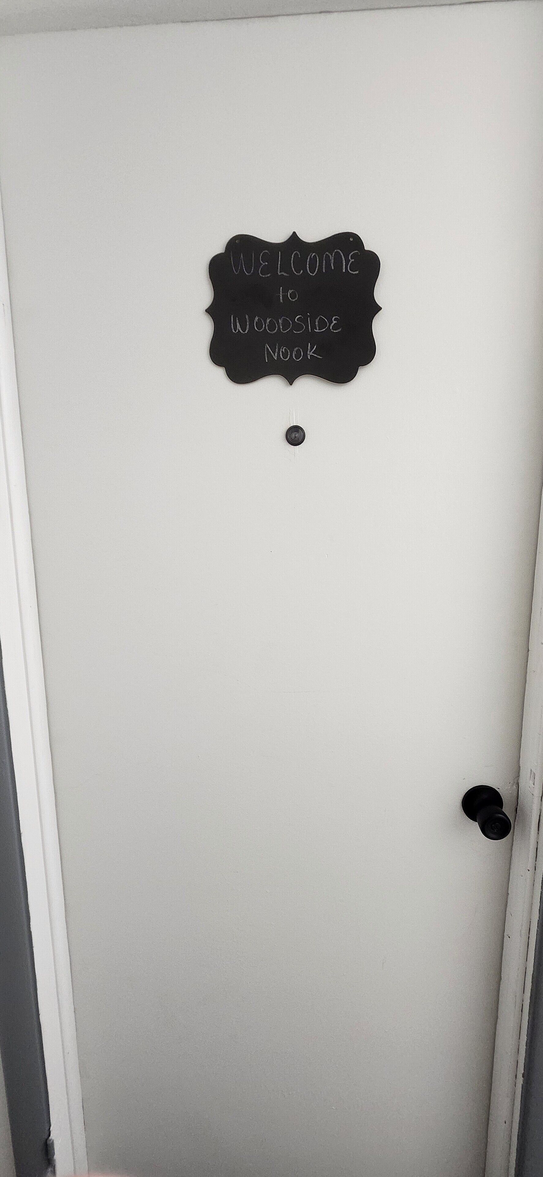 Una porta con un cartello nero che riporta la scritta “Welcome to Woodside Book”.