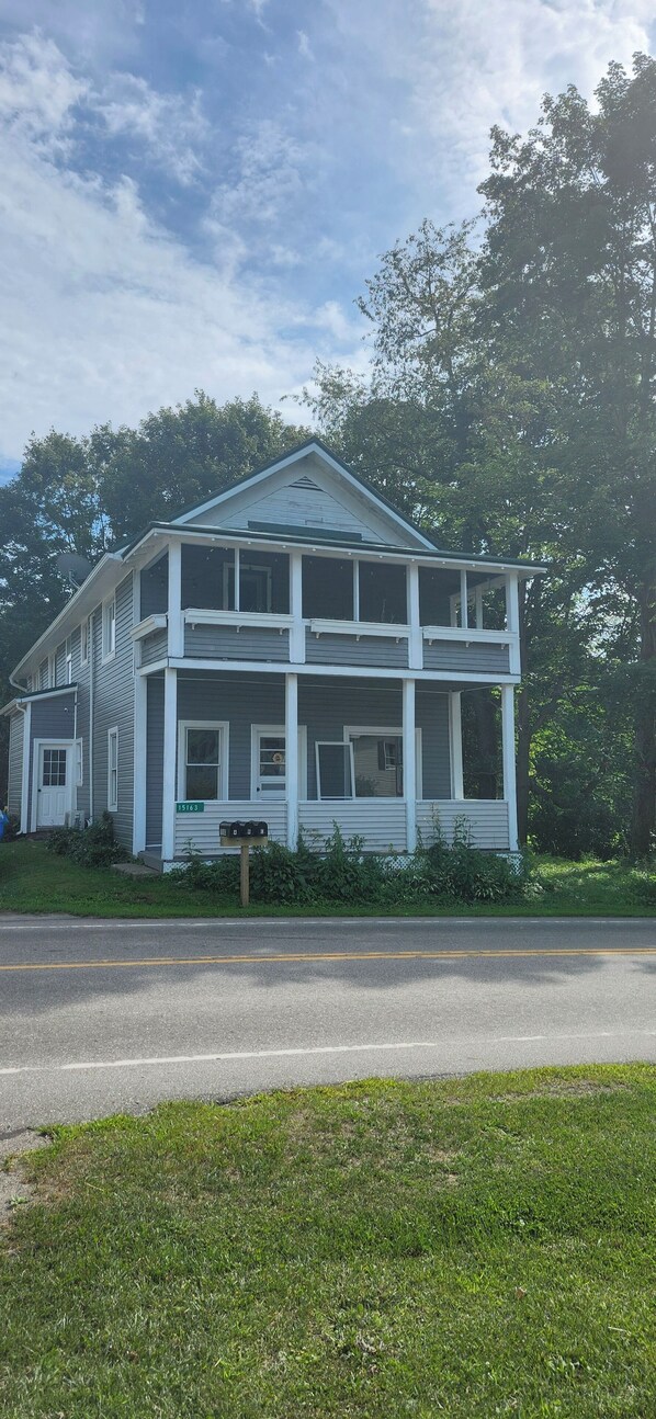 A two-story house with a porch, a mailbox, and a street in front.