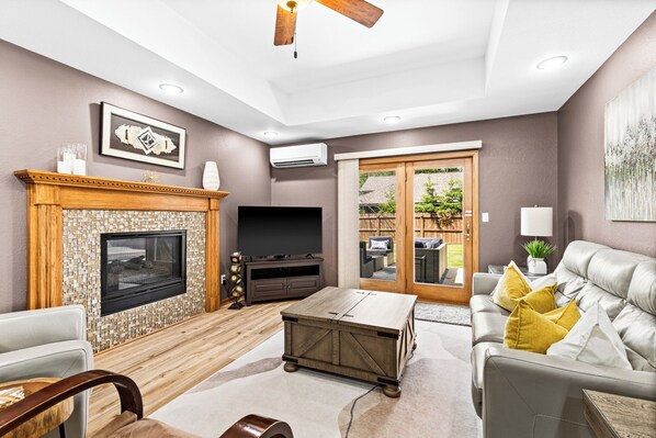 A living room with a fireplace, television, sofa, and a ceiling fan.
