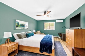A bedroom with a bed, nightstand, dresser, TV, and a ceiling fan.