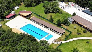 An aerial view of a property with a large swimming pool, surrounded by lush greenery and a few buildings. - The Life Nest Hotel (Saray)