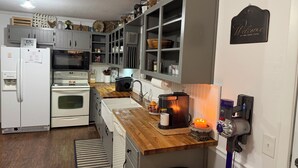A kitchen with grey cabinets, a wooden countertop, a stove, a microwave, and a coffee maker. - Farm Stay Near Town - Animals, Fire Pit, & Privacy - close to wedding venues (Georgetown)