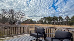 A wooden deck with a table and two chairs, overlooking a grassy field and trees. - Farm Stay Near Town - Animals, Fire Pit, & Privacy - close to wedding venues (Georgetown)