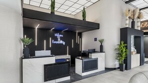 A reception desk with a neon sign, potted plants, and a modern interior design. - Red Lion Inn & Suites Kansas City (Kansas City)