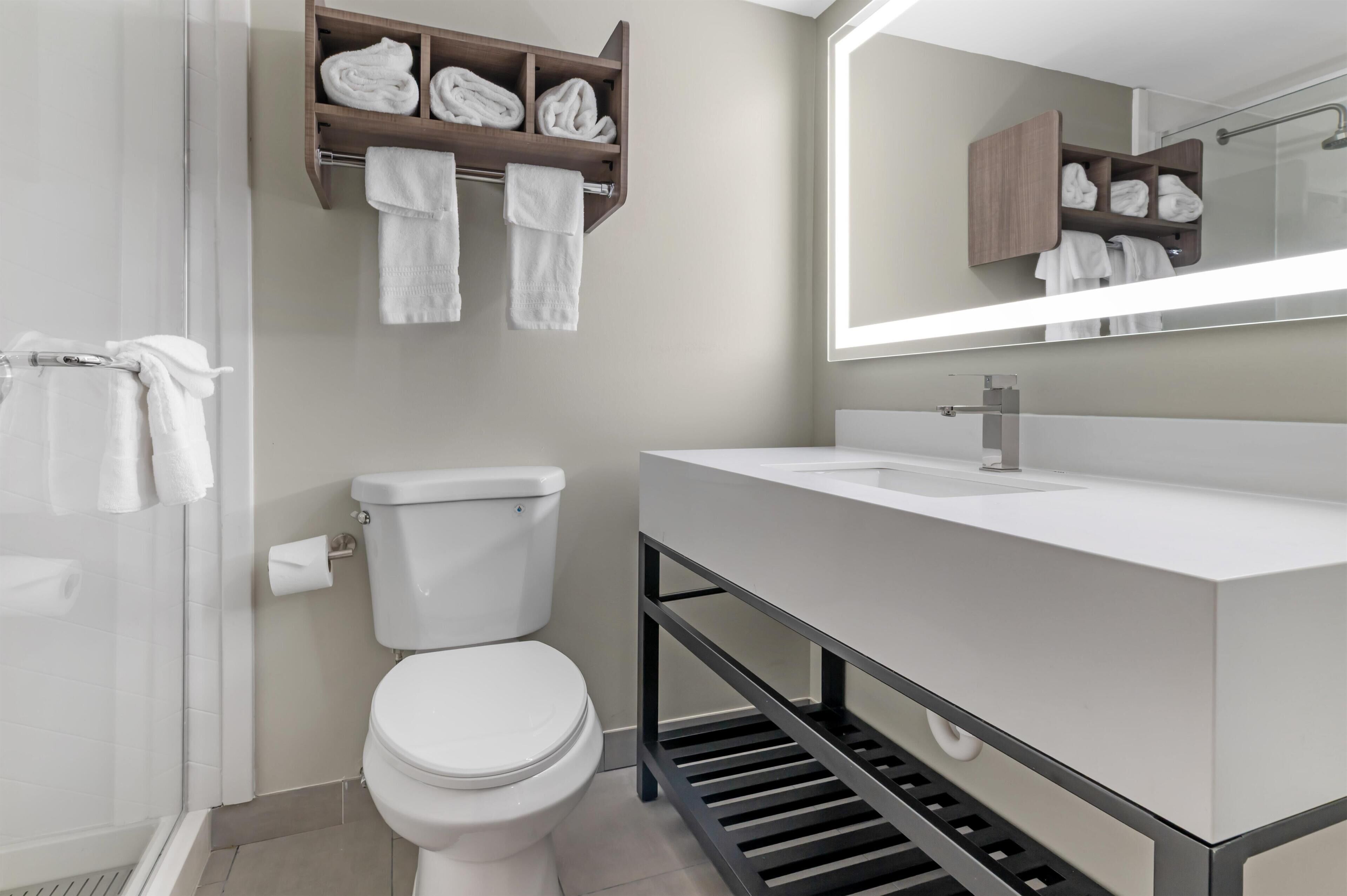 A modern bathroom with a toilet, a sink, a shower, and a towel rack.