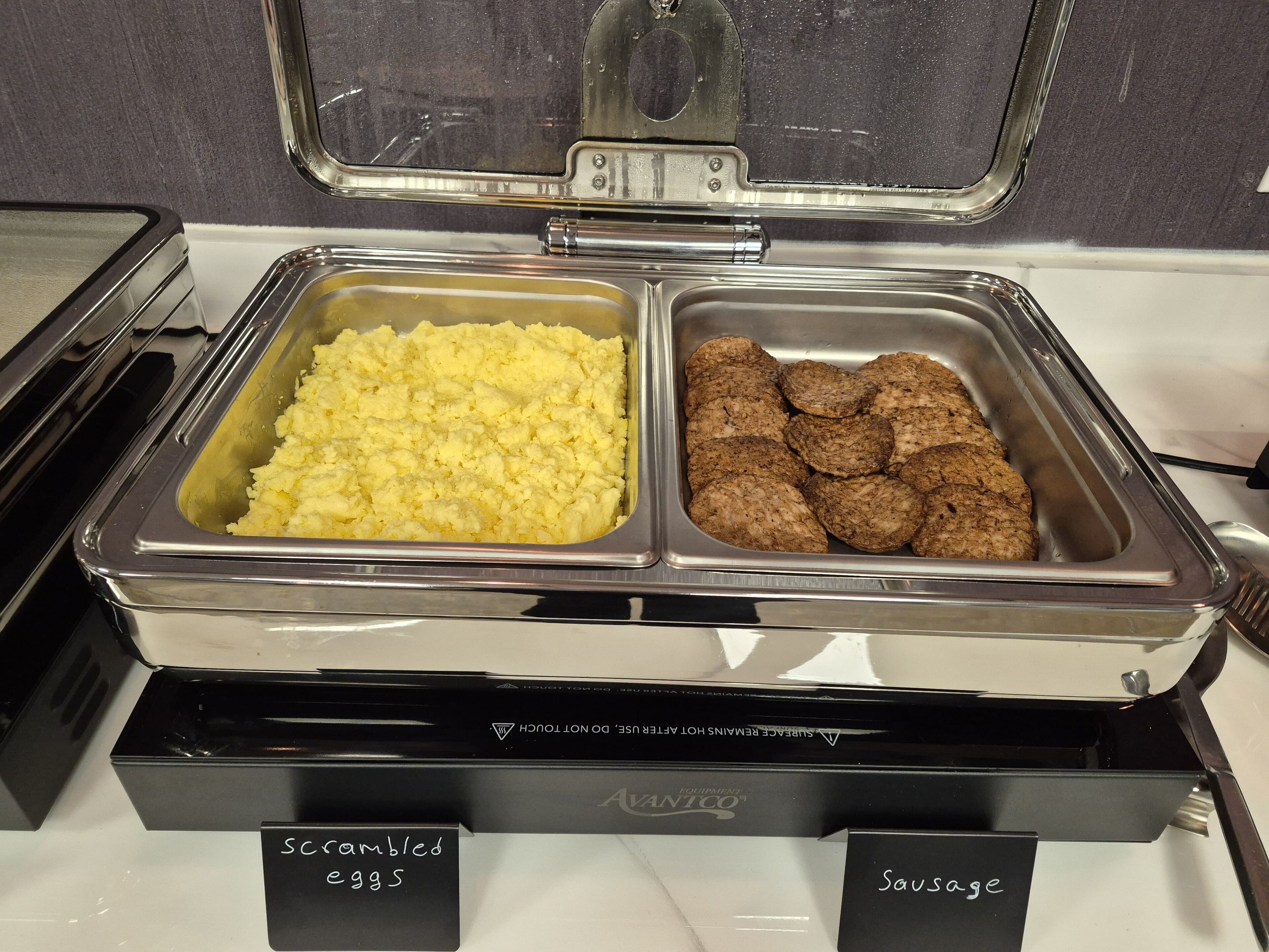 A buffet with scrambled eggs and sausage.